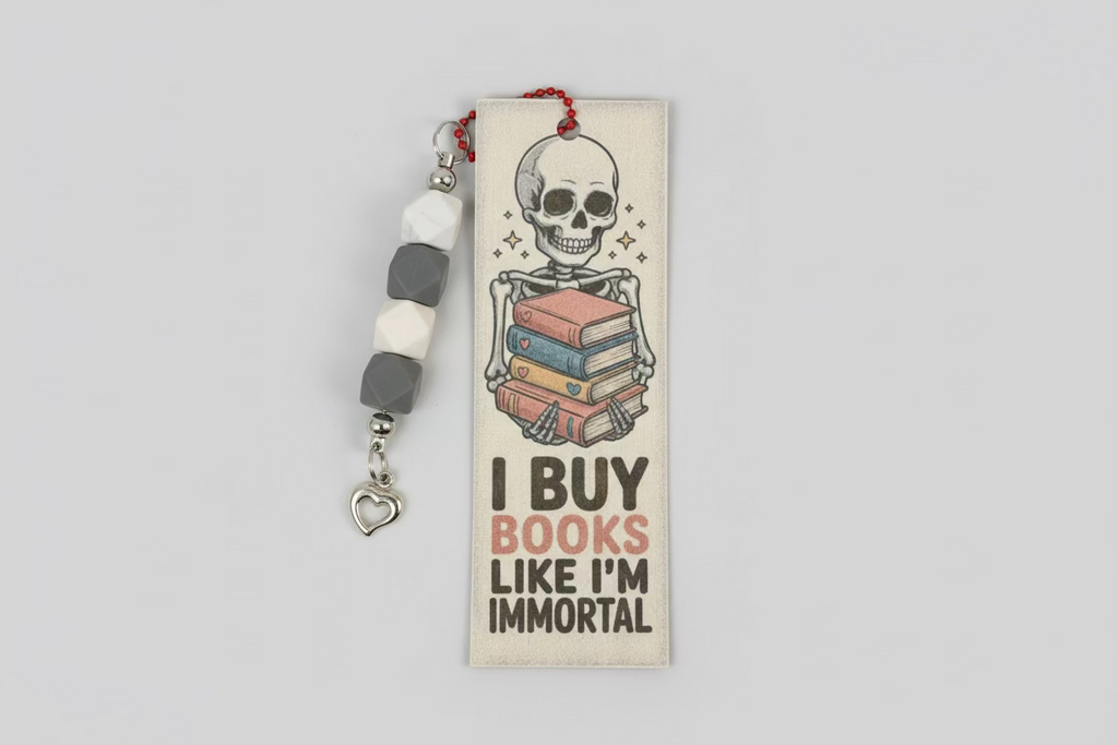 Bookmark with skeleton holding books and text 'I Buy Books Like I'm Immortal' on a dark background.